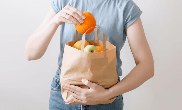 World Environment Day Hand holding a reusable eco-friendly shopping bag full of vegetables and fruits.