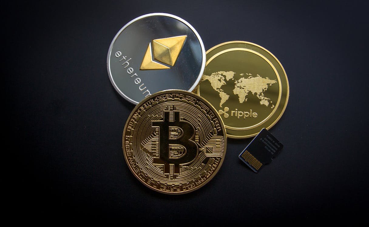 Moeda física do Bitcoin sobre um fundo de gráficos financeiros, representando o guia de criptomoedas para iniciantes.